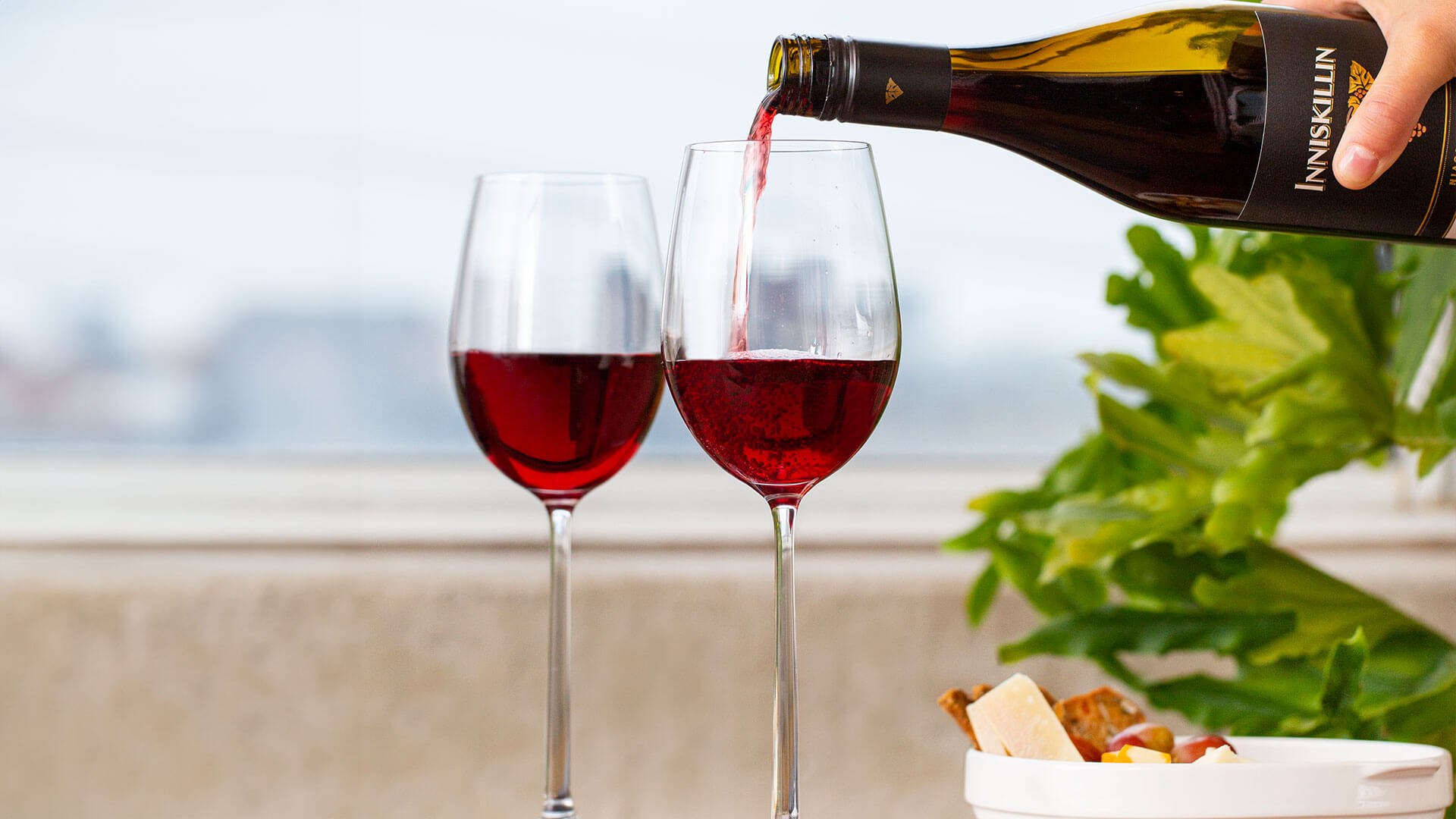 Inniskillin Montague Vineyard Pinot Noir being poured into red wine glasses on outside balcony.